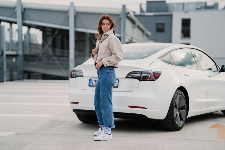 Frau vorm Tesla Auto Abo