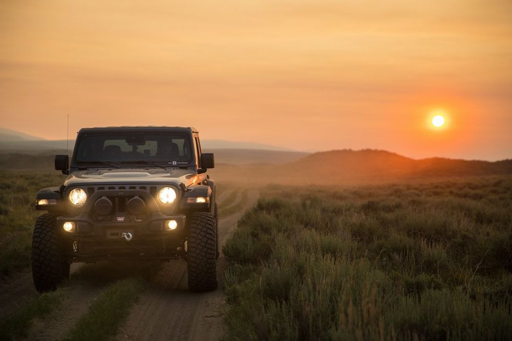 Jeep vor Sonnenuntergang im steinigen, leicht bergigem Gelände.