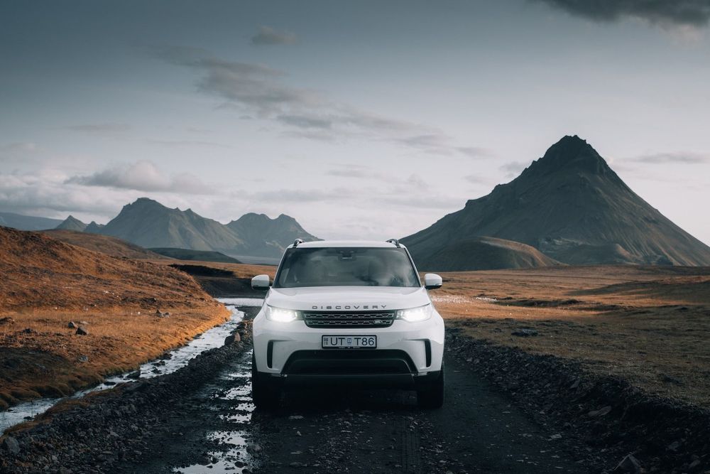 Weißer Land Rover Discovery im Gelände vor einem Berg